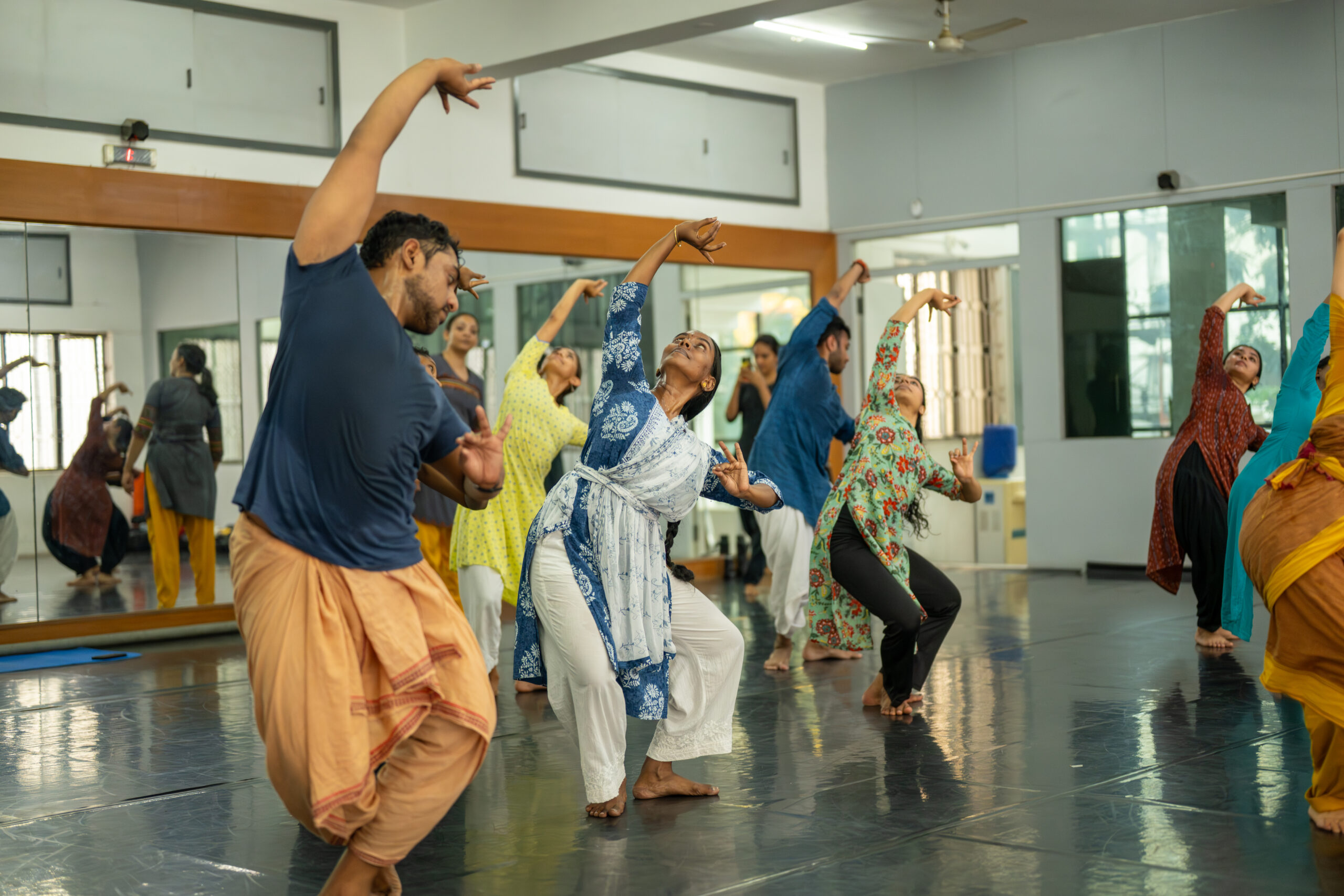Several dancers in a studio stretching over to one side.